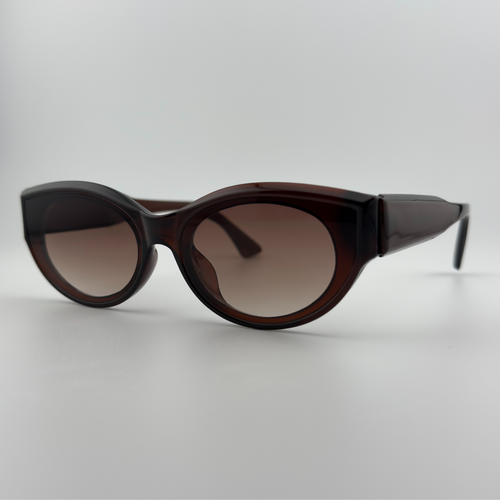 Velra Elyria – lunettes de soleil, vue angle 3/4 : design arrondi avec monture marron transparente et verres bruns pour un style rétro et doux.
